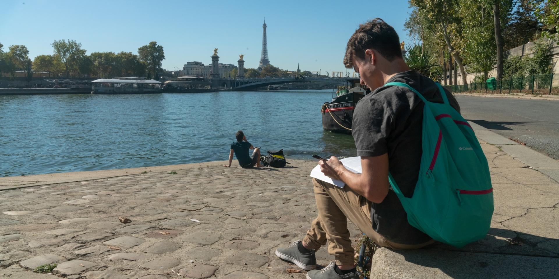 A student writing on the banks of the Seine in Paris